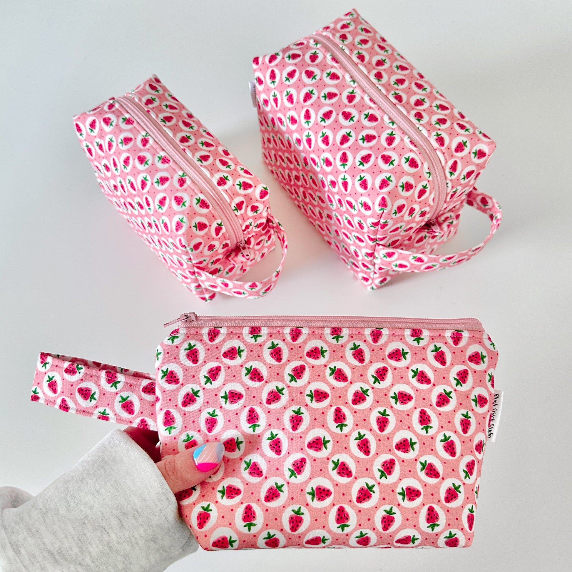 Set of pink cotton makeup bags with strawberry pattern on a white background
