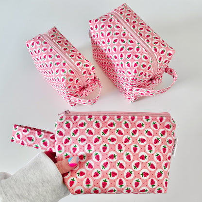 Set of pink cotton makeup bags with strawberry pattern on a white background