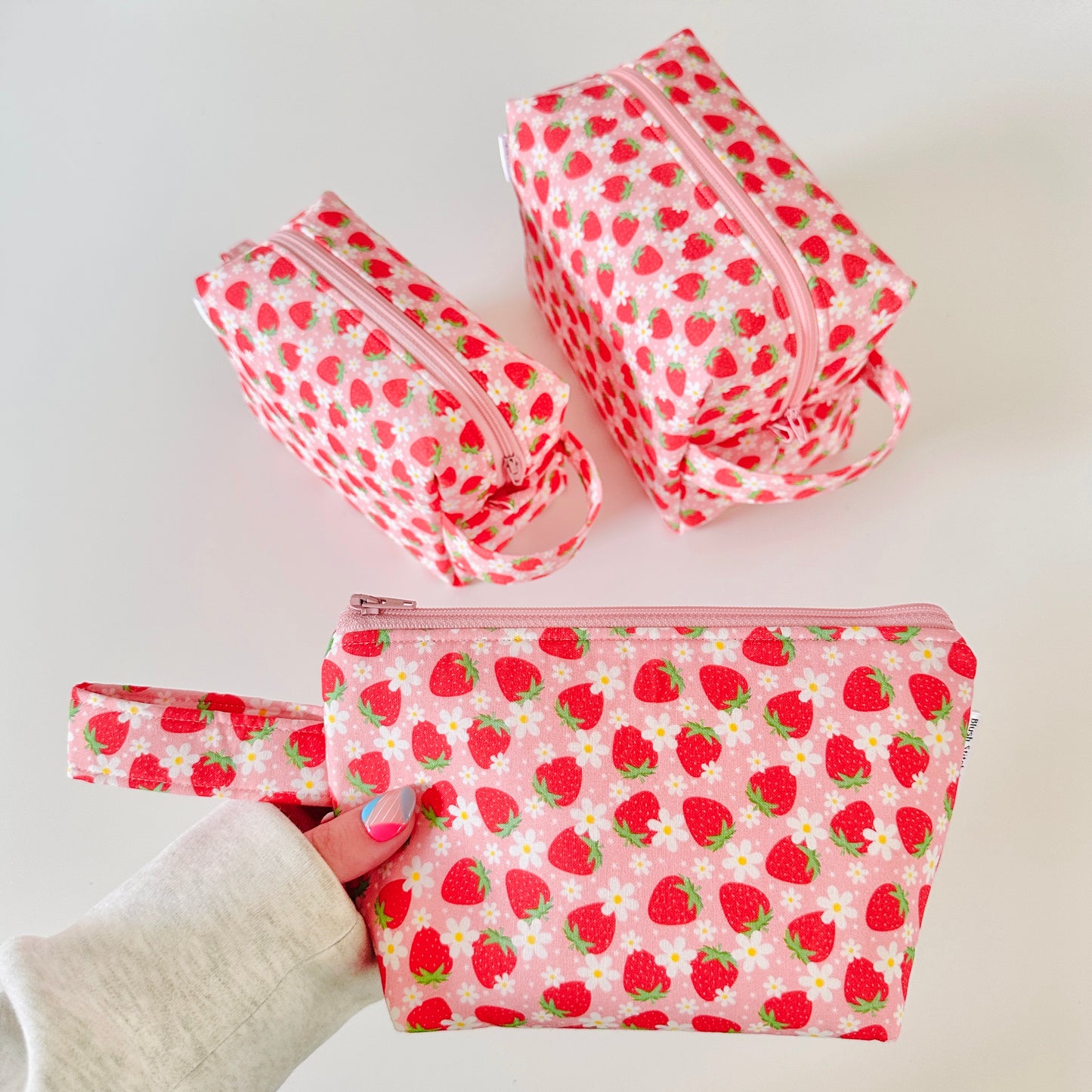 Set of strawberry-patterned pouches on a white background