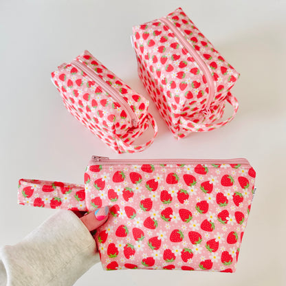 Set of strawberry-patterned pouches on a white background