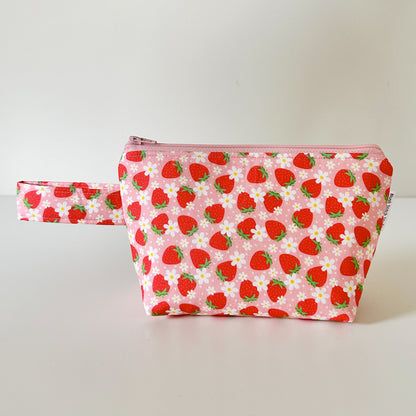 Pink pouch with strawberry pattern on a white background