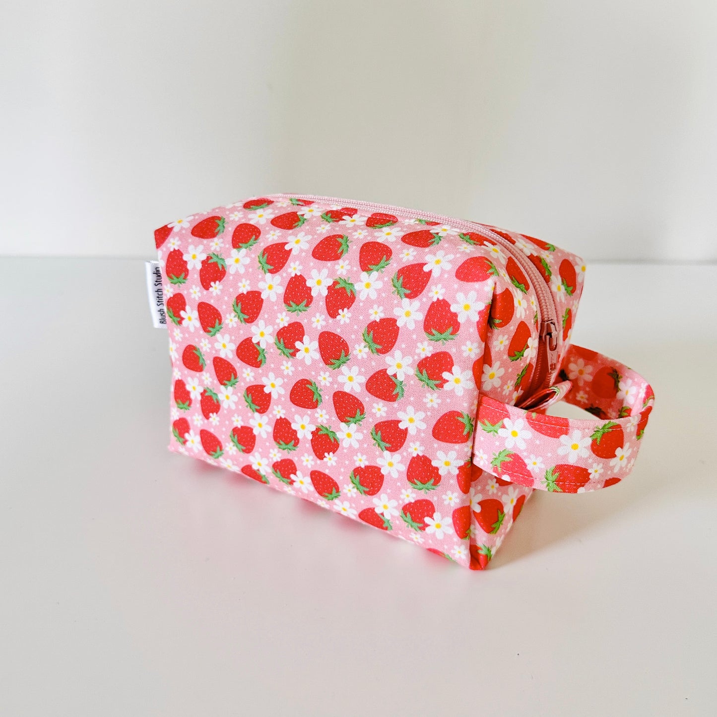 Pink pouch with strawberry pattern on a white background