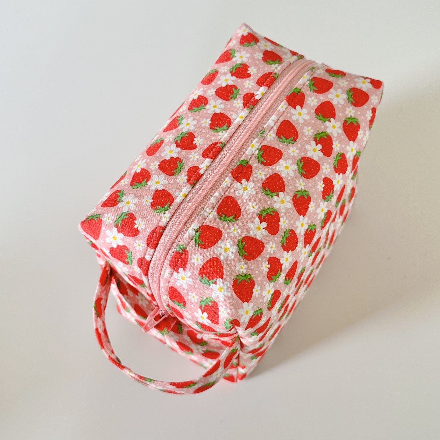 Cosmetic bag with strawberry pattern on a light background
