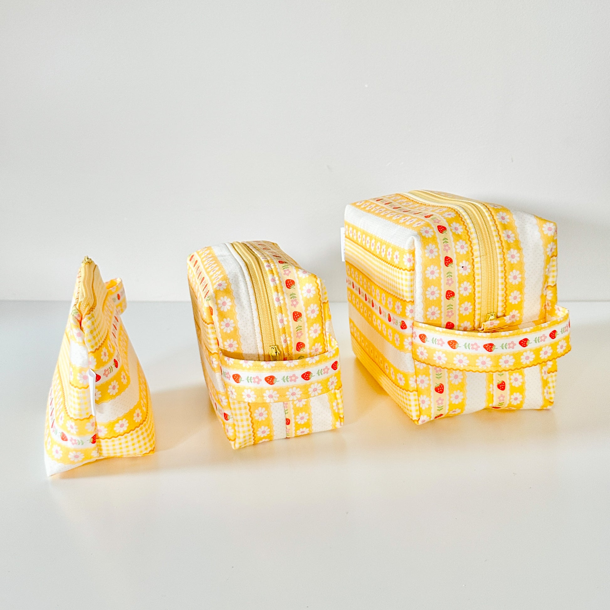 Yellow strawberry patterned makeup cosmetic bags on a white background