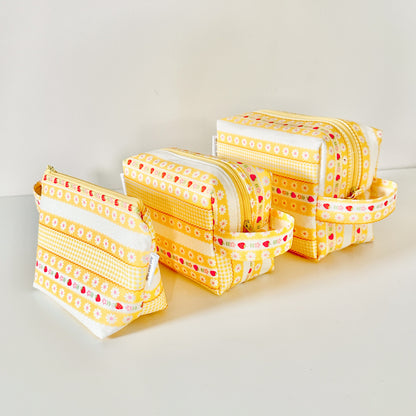 Yellow strawberry patterned makeup cosmetic bags on a white background