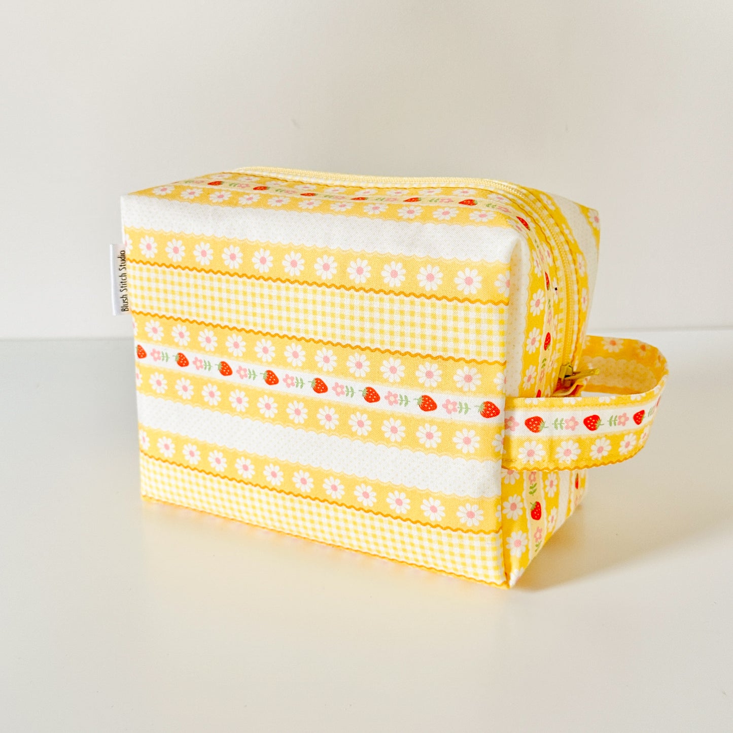 Yellow strawberry patterned makeup cosmetic bags on a white background