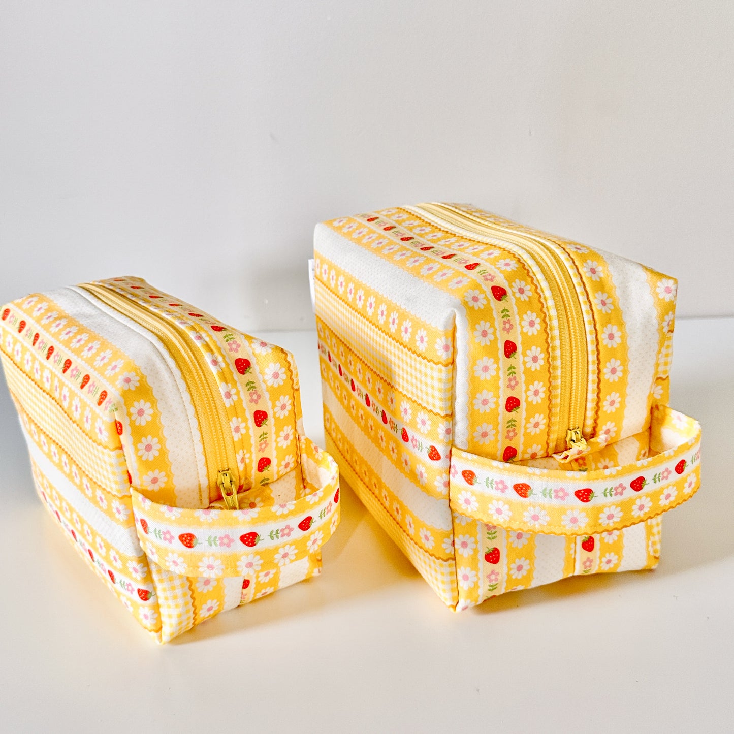 Yellow strawberry patterned makeup cosmetic bags on a white background