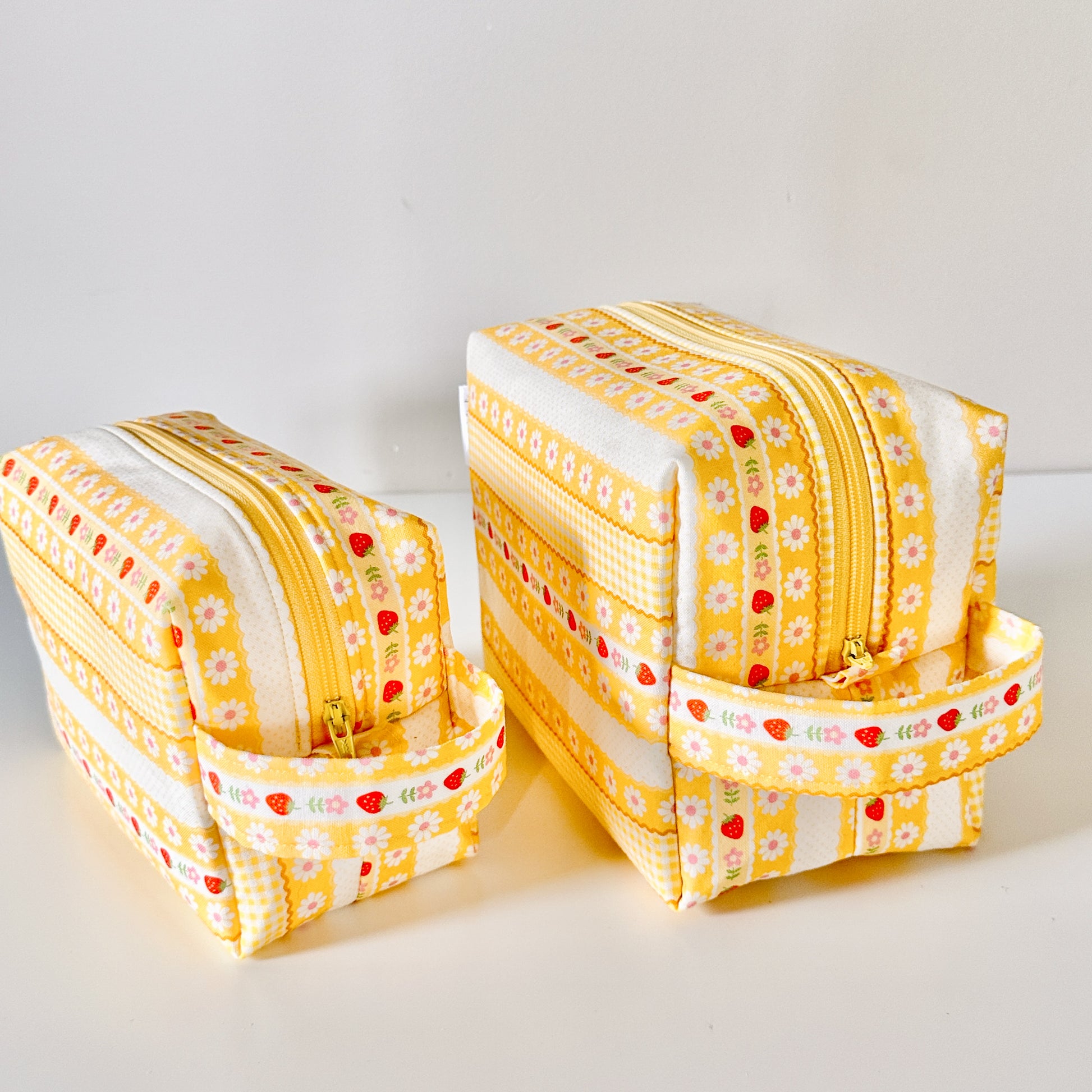 Yellow strawberry patterned makeup cosmetic bags on a white background