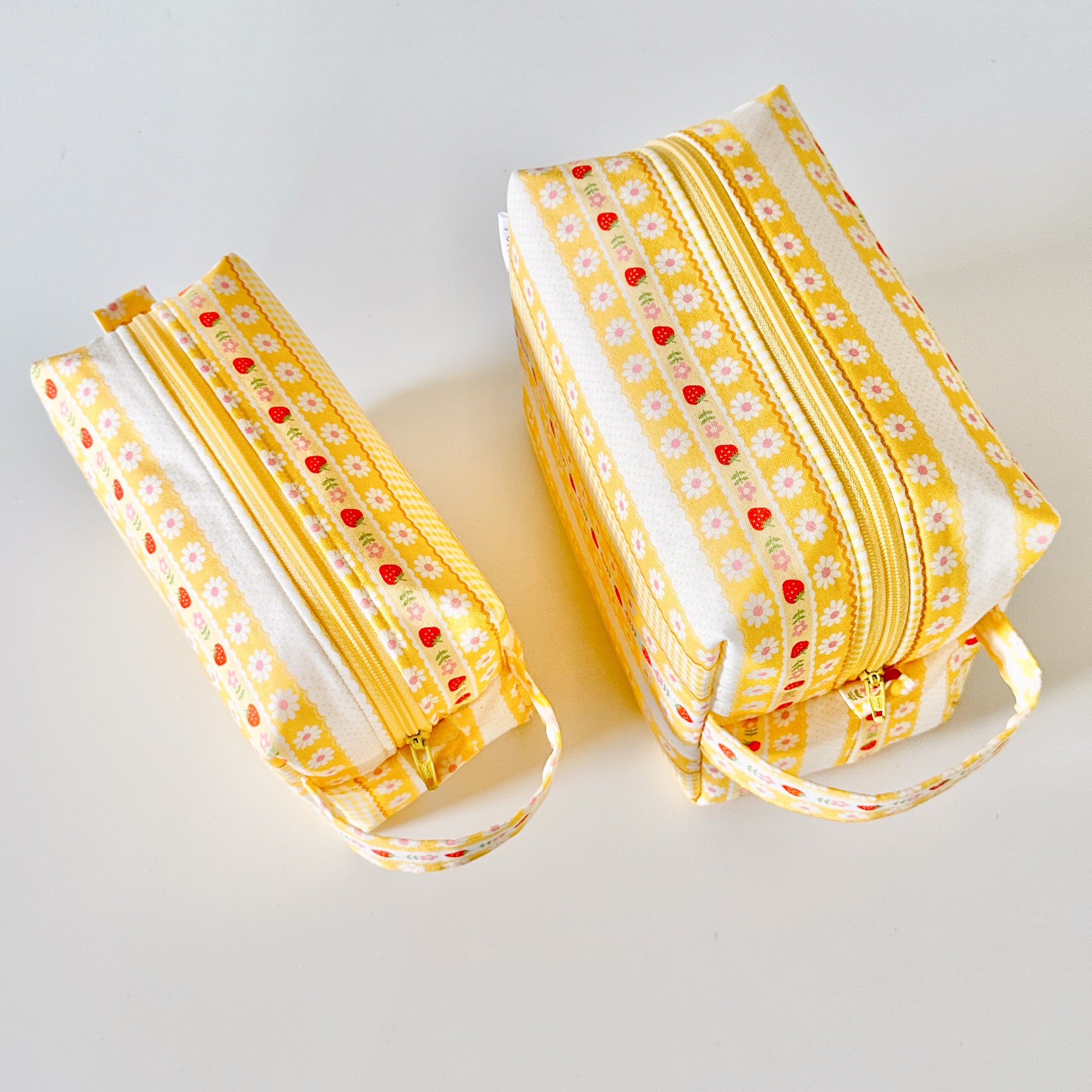 Yellow strawberry patterned makeup cosmetic bags on a white background