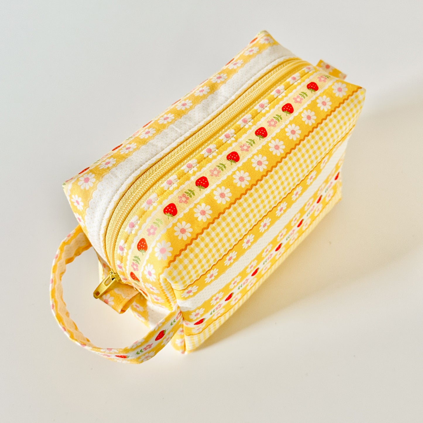 Yellow strawberry patterned makeup cosmetic bags on a white background