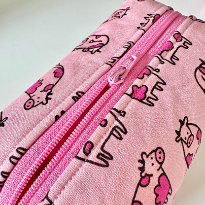 Pink pouch with cow pattern and zipper on a light gray background