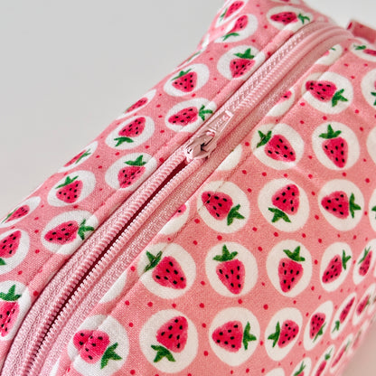 Pink pouch with strawberry pattern on a light gray background