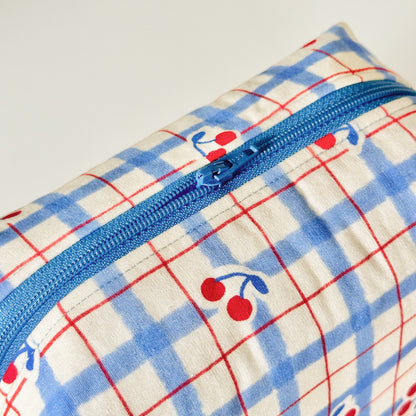 Pouch with blue and red plaid pattern and cherry design on a white background