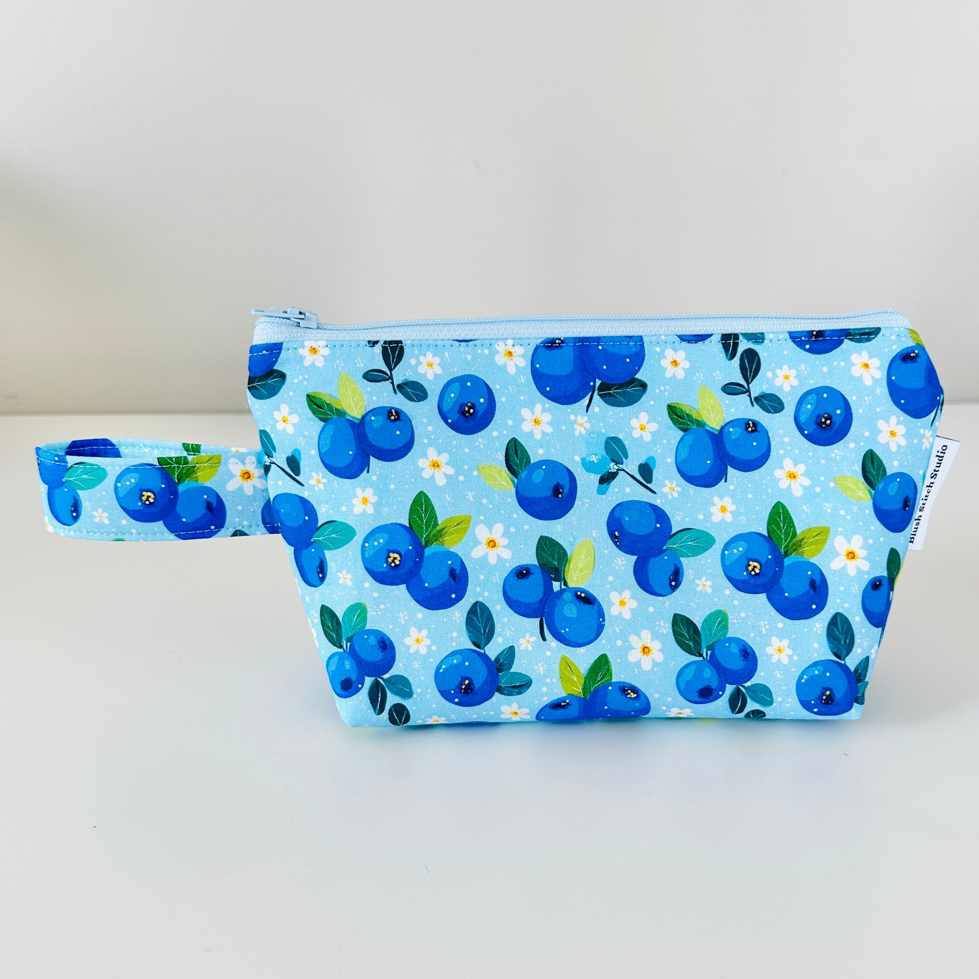 Blueberry-patterned pouch on a light gray background