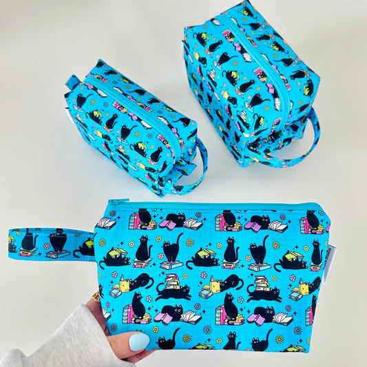 Set of blue makeup bags with black cat pattern on a light gray background