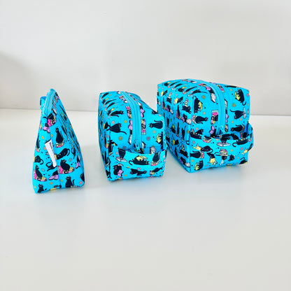 Three blue bags with black cat pattern on a white background