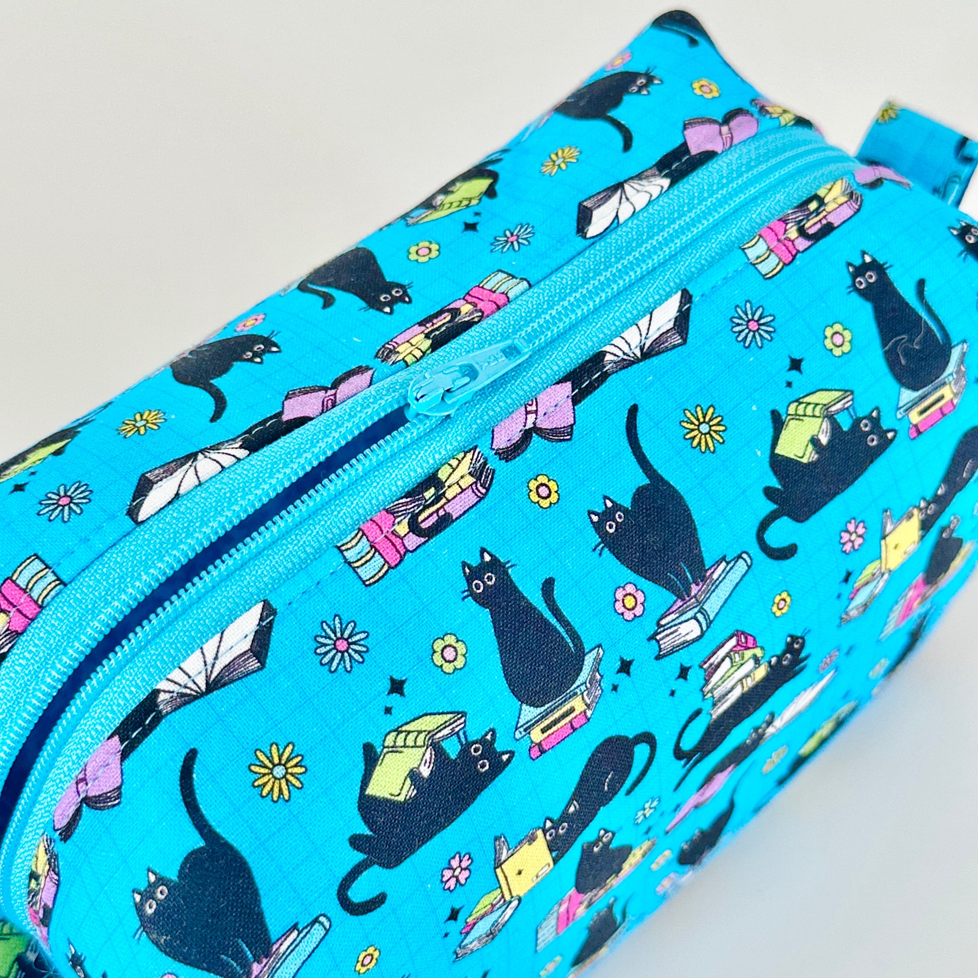 Blue pencil case with black cat pattern on a light gray background