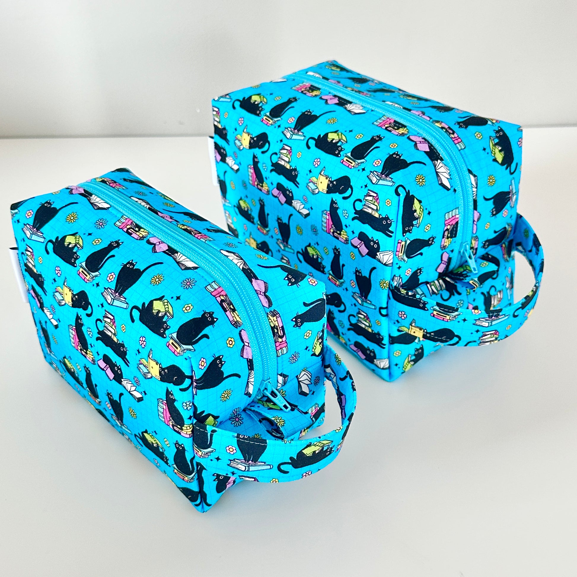 Two blue makeup bags with black cat pattern on a white background