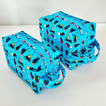 Two blue makeup bags with black cat pattern on a white background
