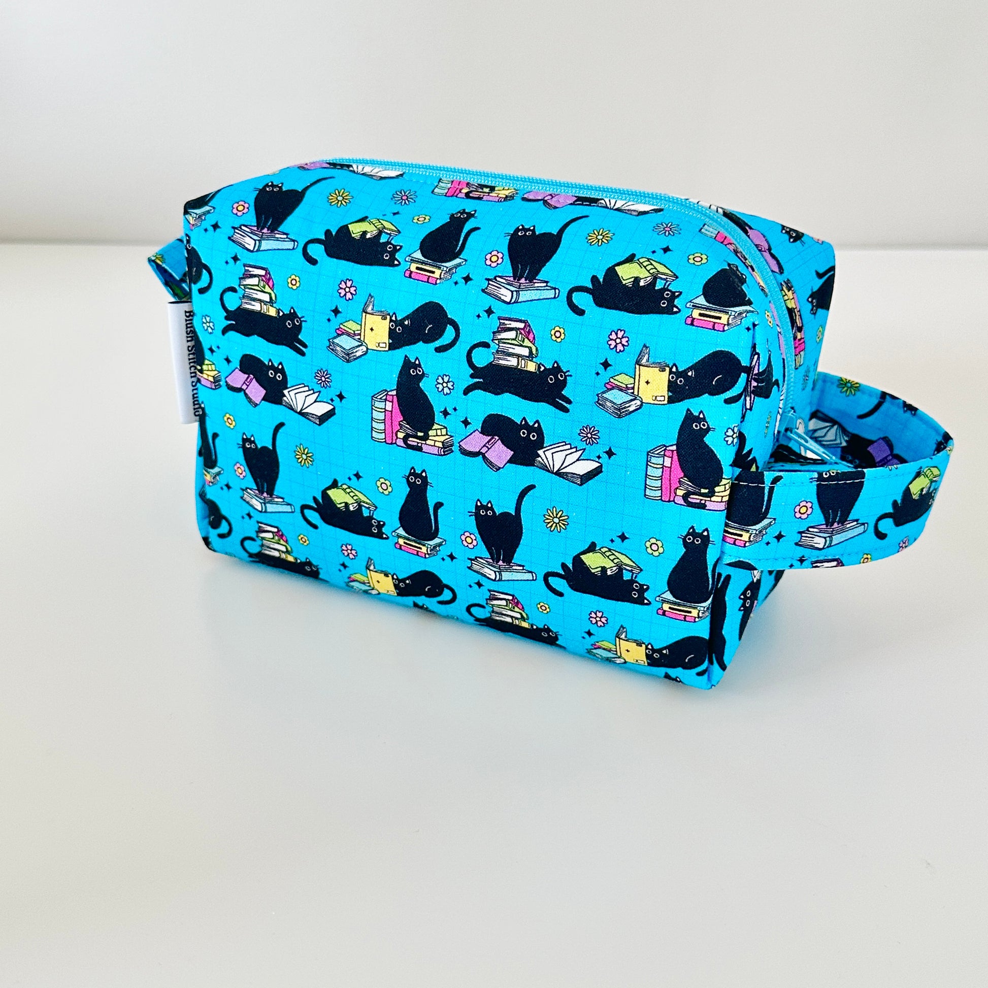 Blue pouch with black cat pattern on a white background