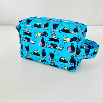 Blue pouch with black cat pattern on a white background