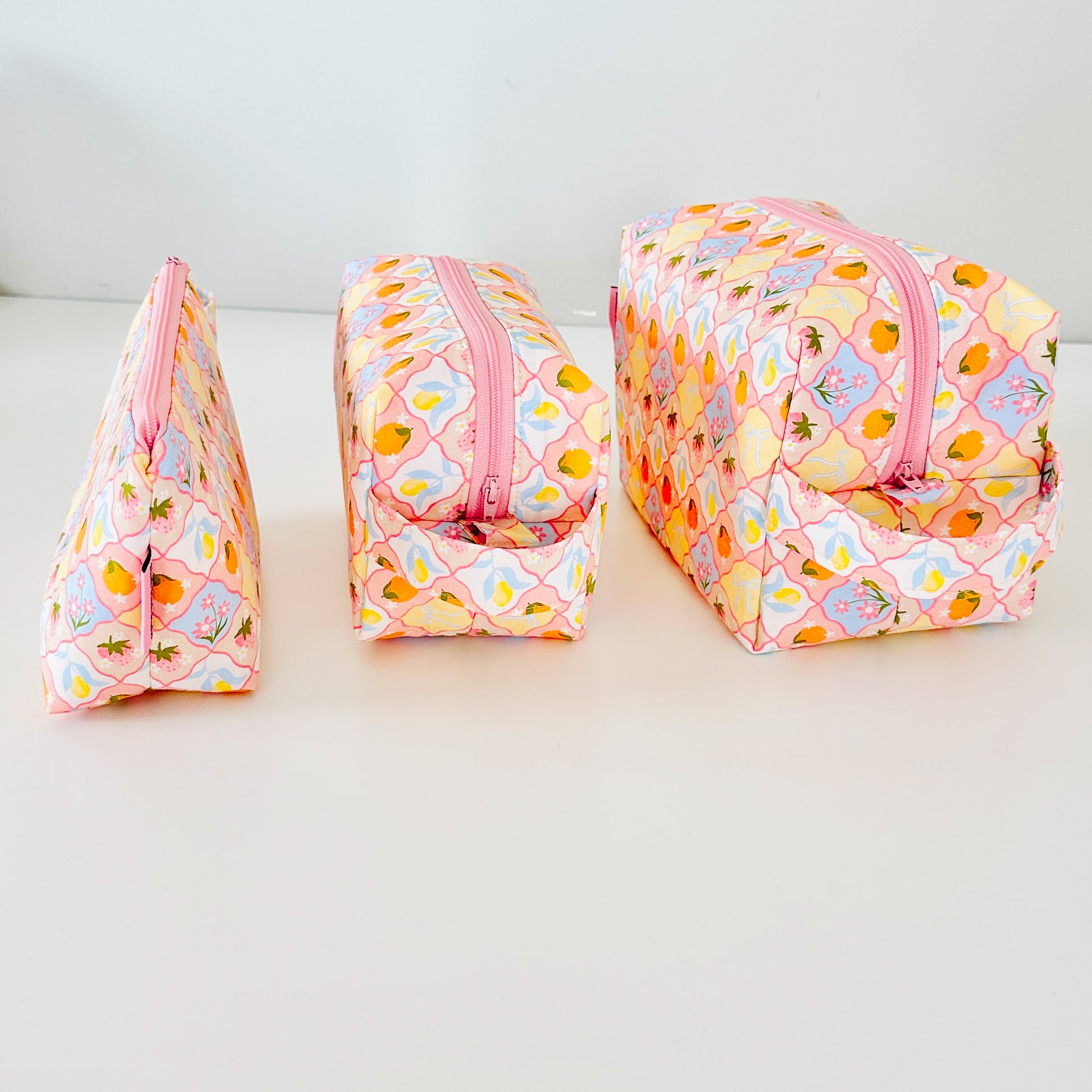 Three colorful fabric bags with pink zippers on a white background