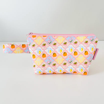 fruit patterned pouch with pink zipper on a light gray background