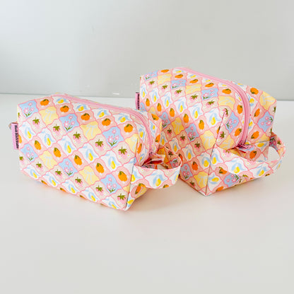 Two fruit patterned makeup bags with pineapple pattern on a white background