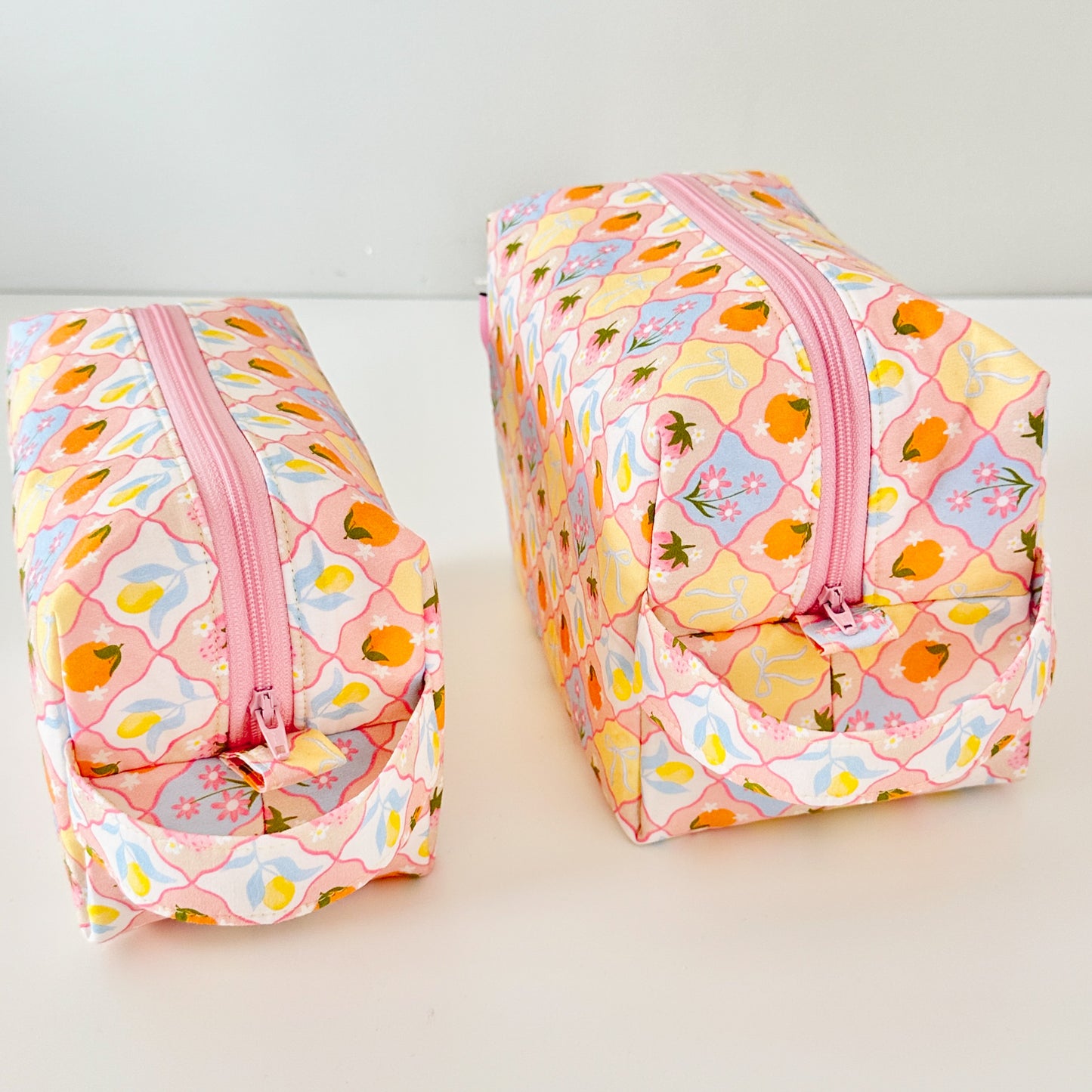 Two floral-patterned bags with pink zippers on a light background