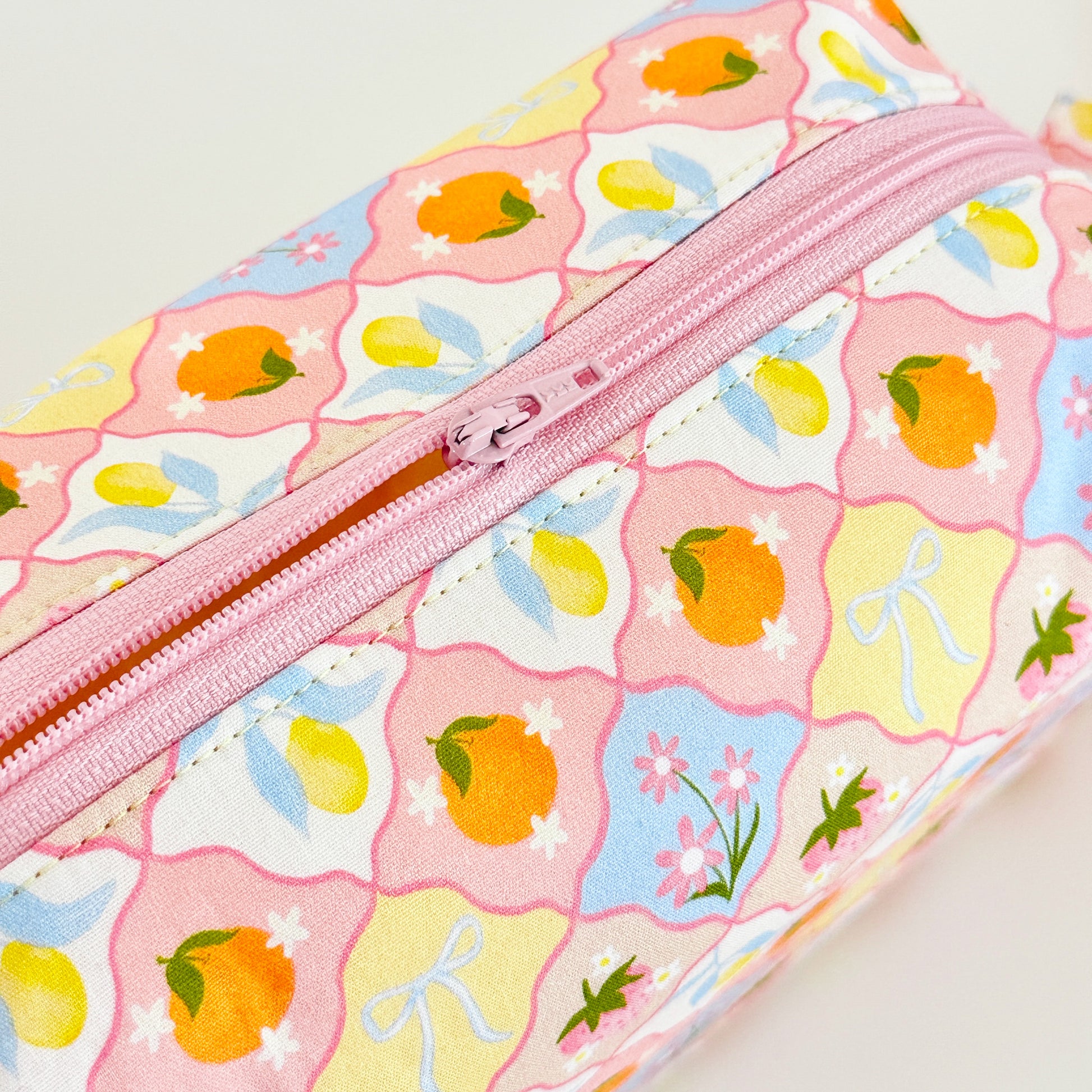 fruit patterned cosmetic bag with pink zipper on a white background