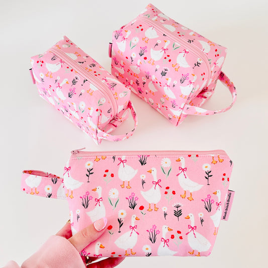 Set of pink pouches with goose and flower pattern on a light background