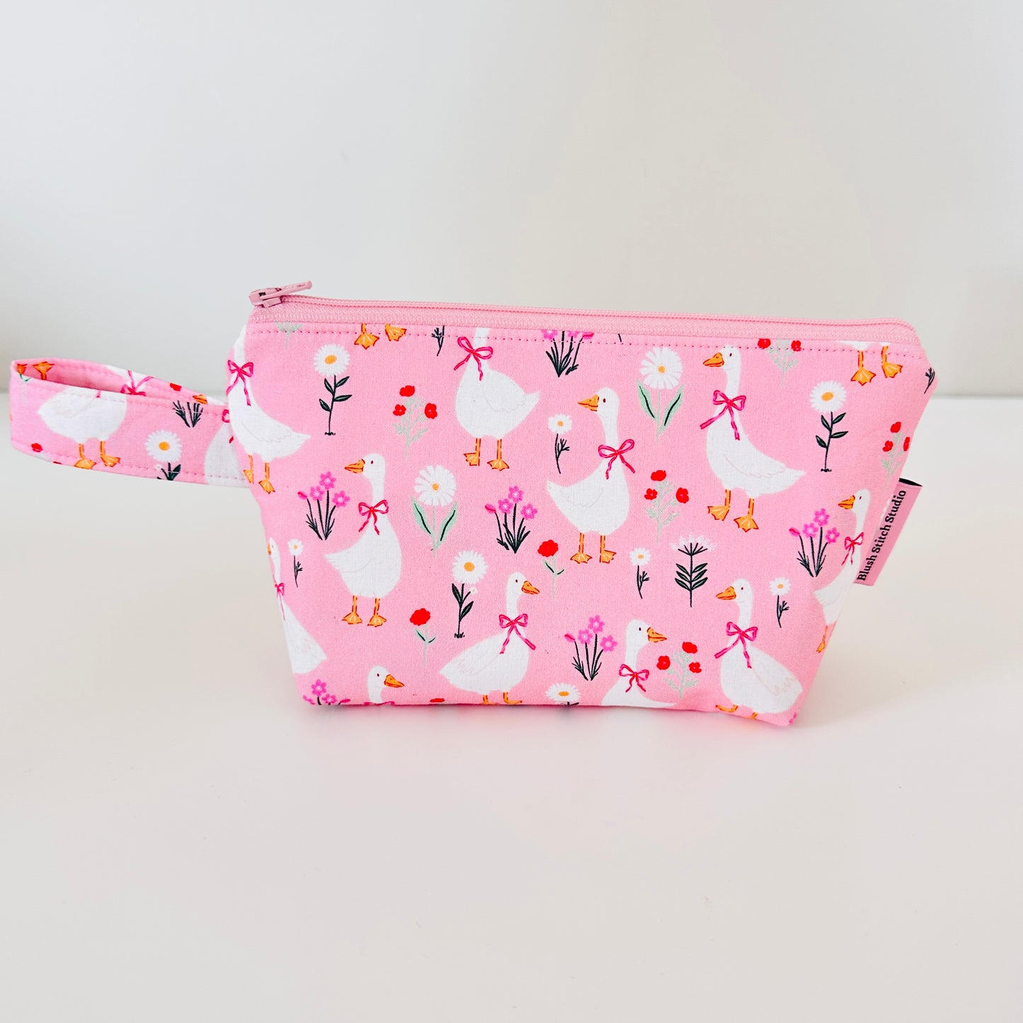 Pink pouch with goose and flower pattern on a white background
