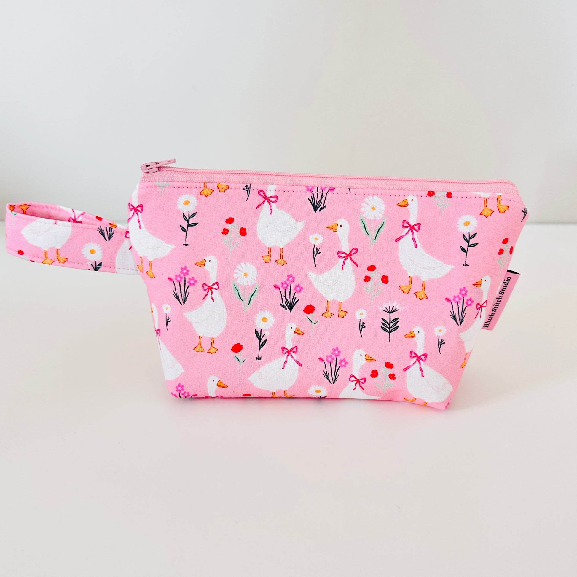 Pink pouch with goose and flower pattern on a white background
