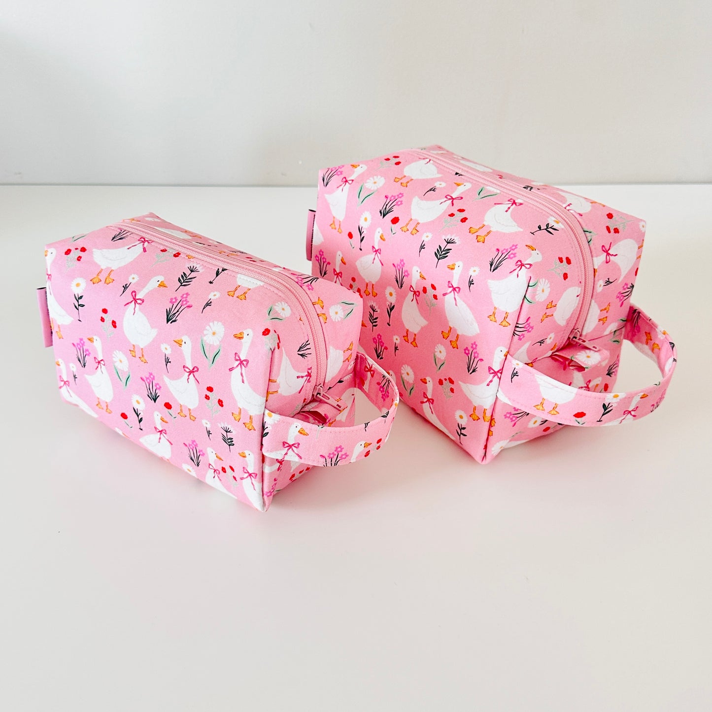 Two pink toiletry bags with floral patterns on a white background