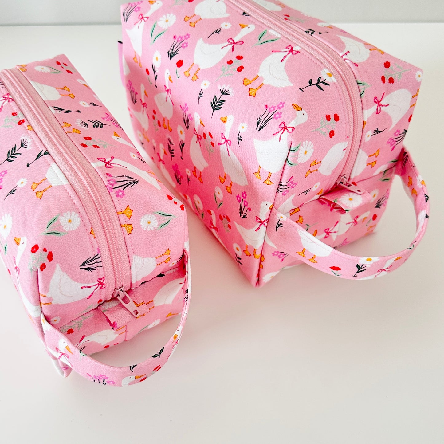 Pink toiletry bag with floral and horse pattern on a white background