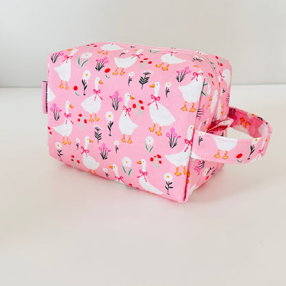 Pink cosmetic bag with duck pattern on a white background