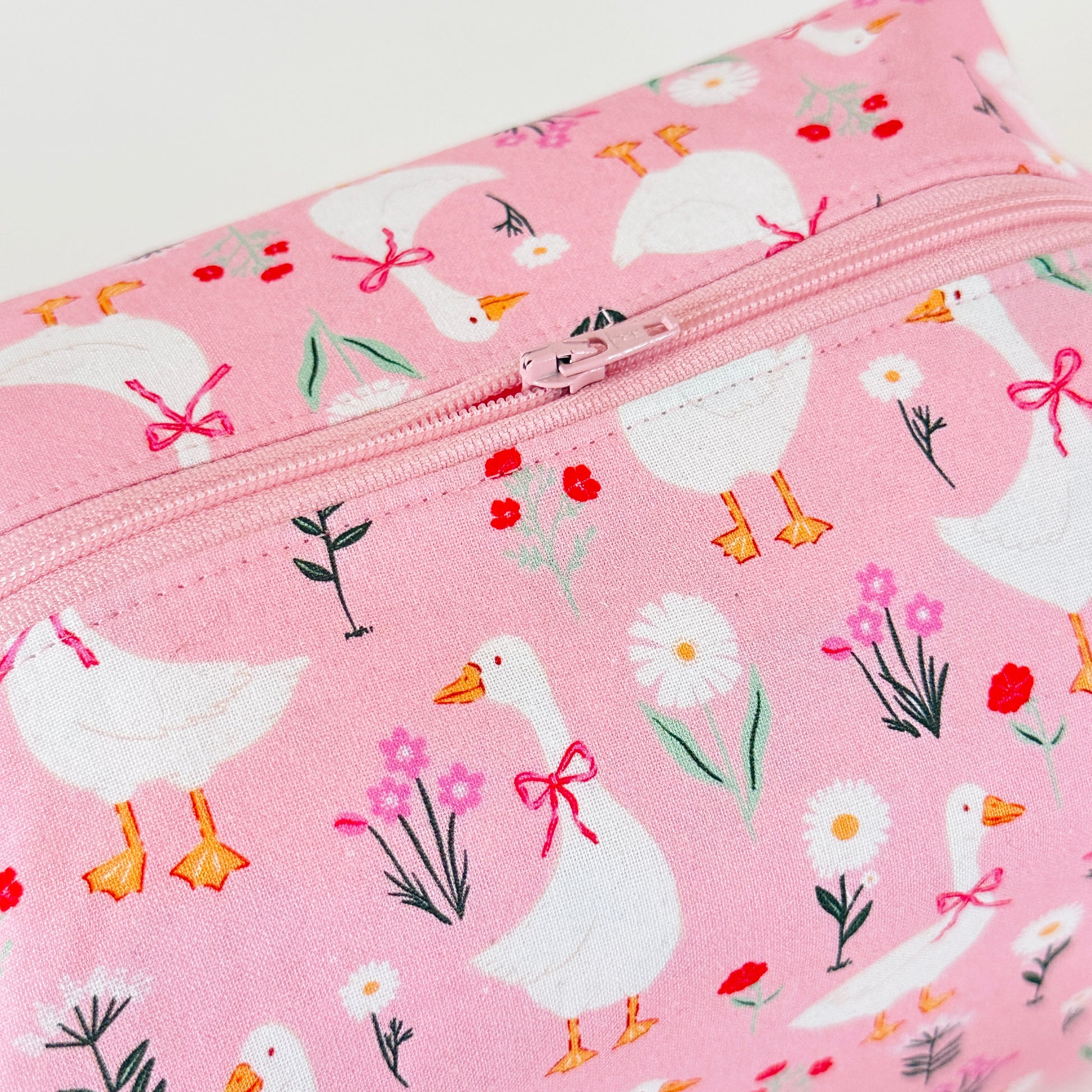 Pink pouch with duck and flower pattern on a white background
