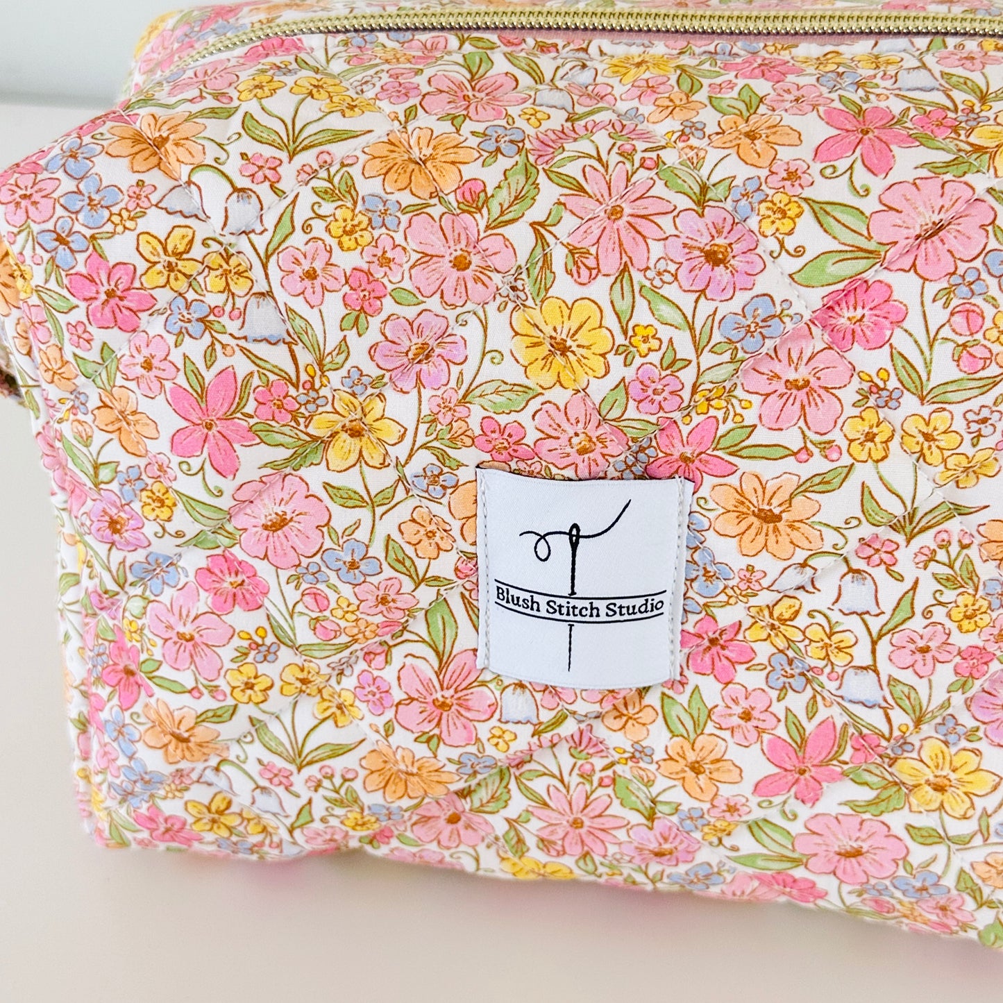 Floral-patterned pouch with a visible brand label on a light background