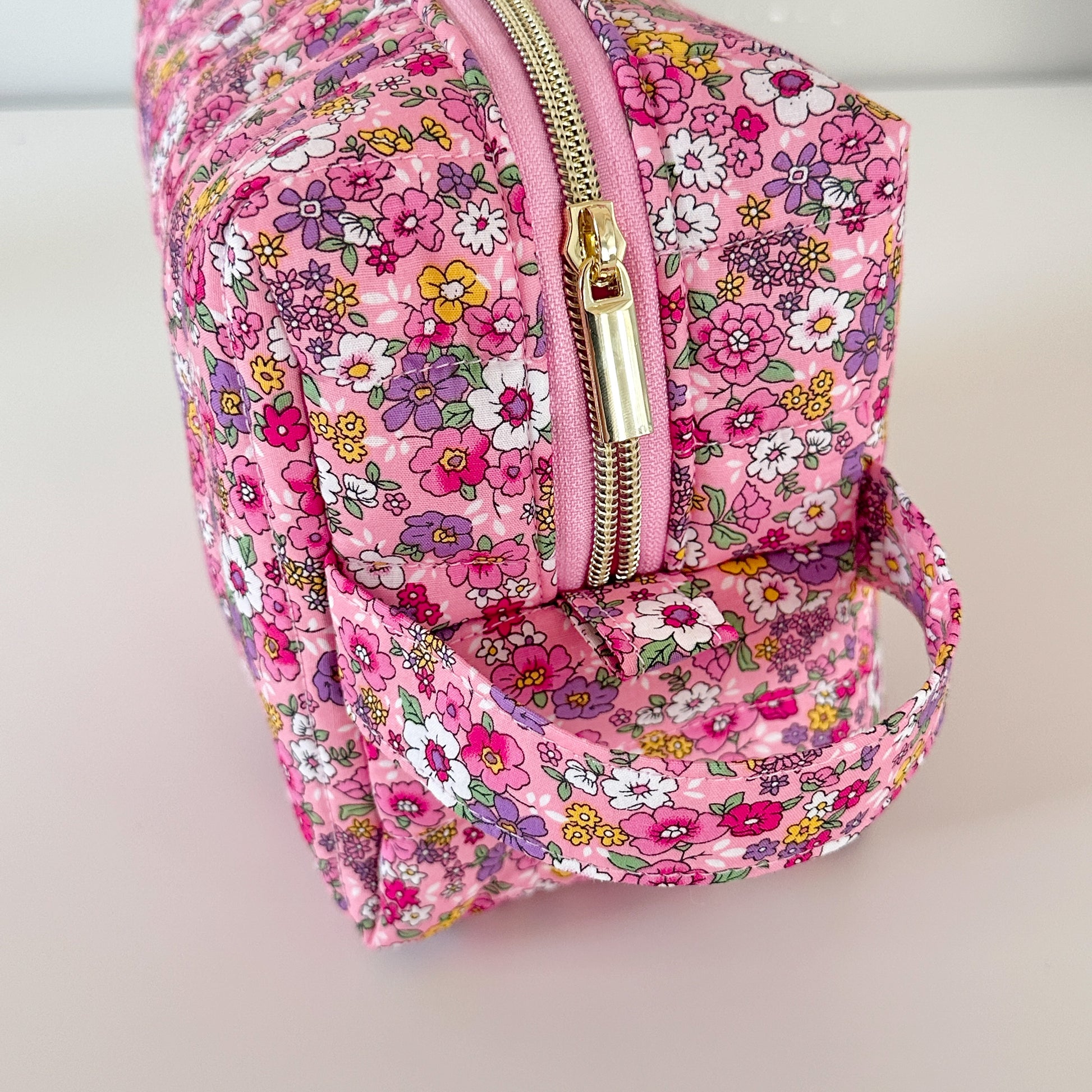 Pink floral backpack with a gold zipper on a light background