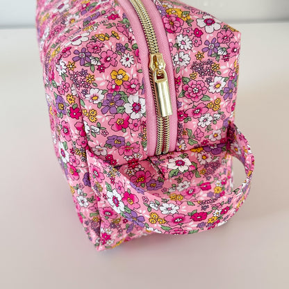 Pink floral backpack with a gold zipper on a light background