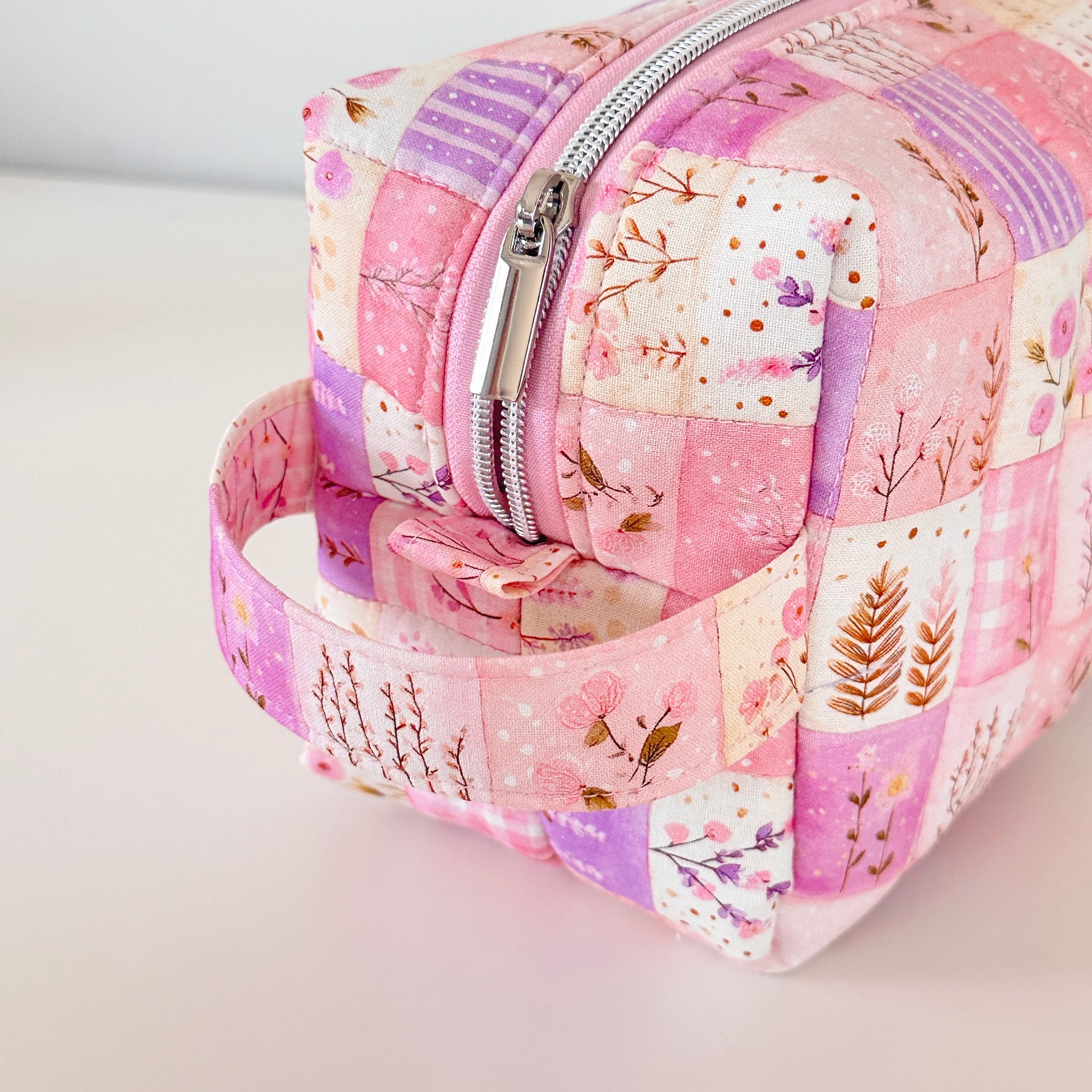 Pink floral patchwork makeup bag with a silver zipper on a light background