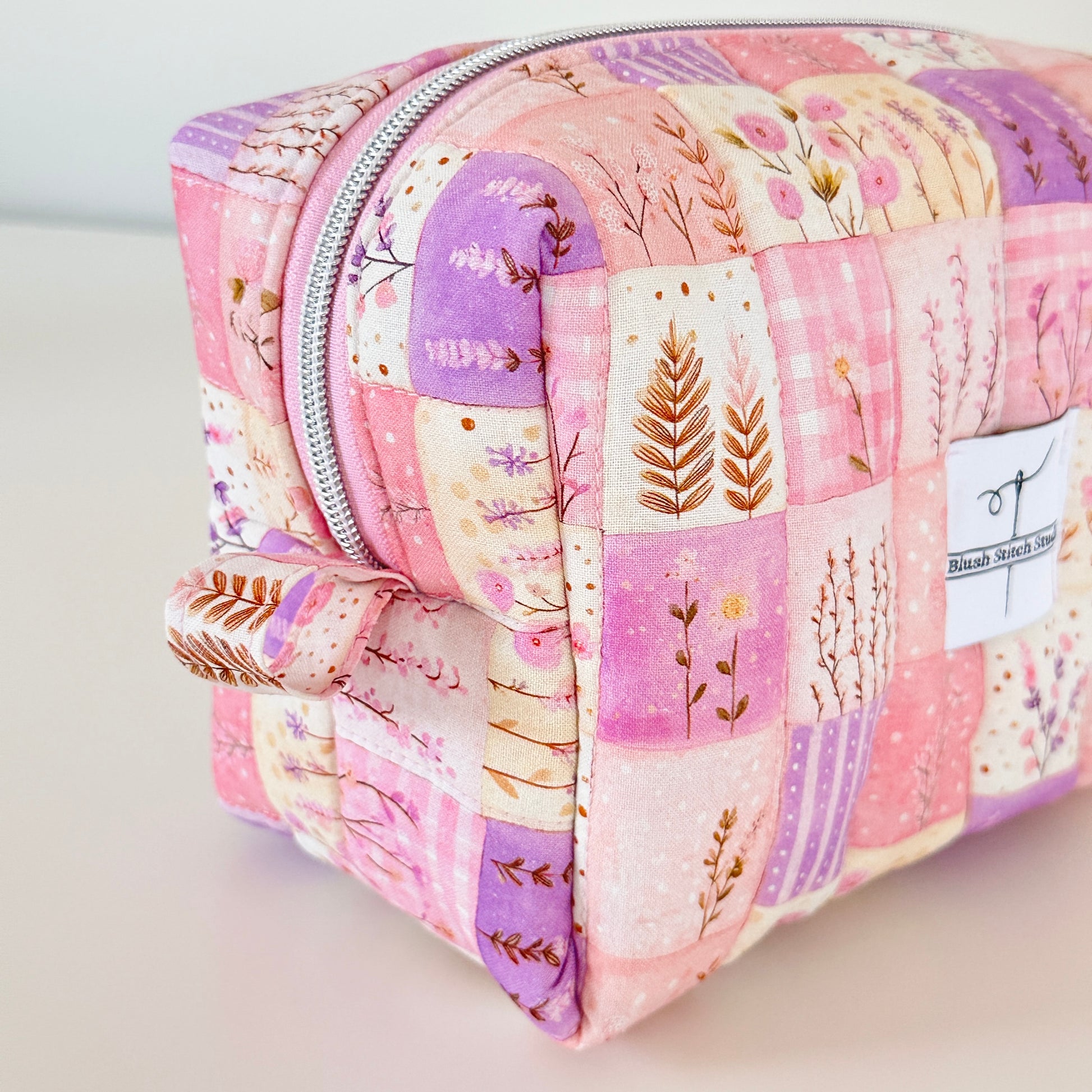 Patchwork-style cosmetic bag with floral patterns on a light background