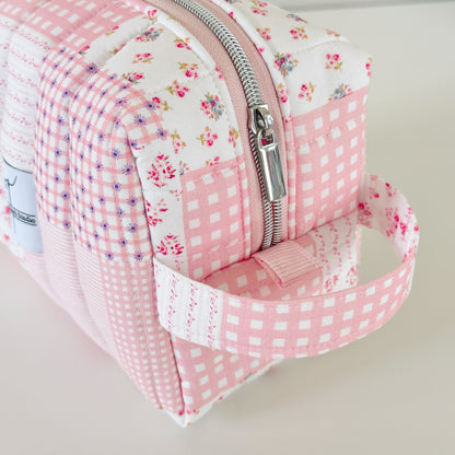 Pink floral and checkered patterned pouch with a zipper on a light background