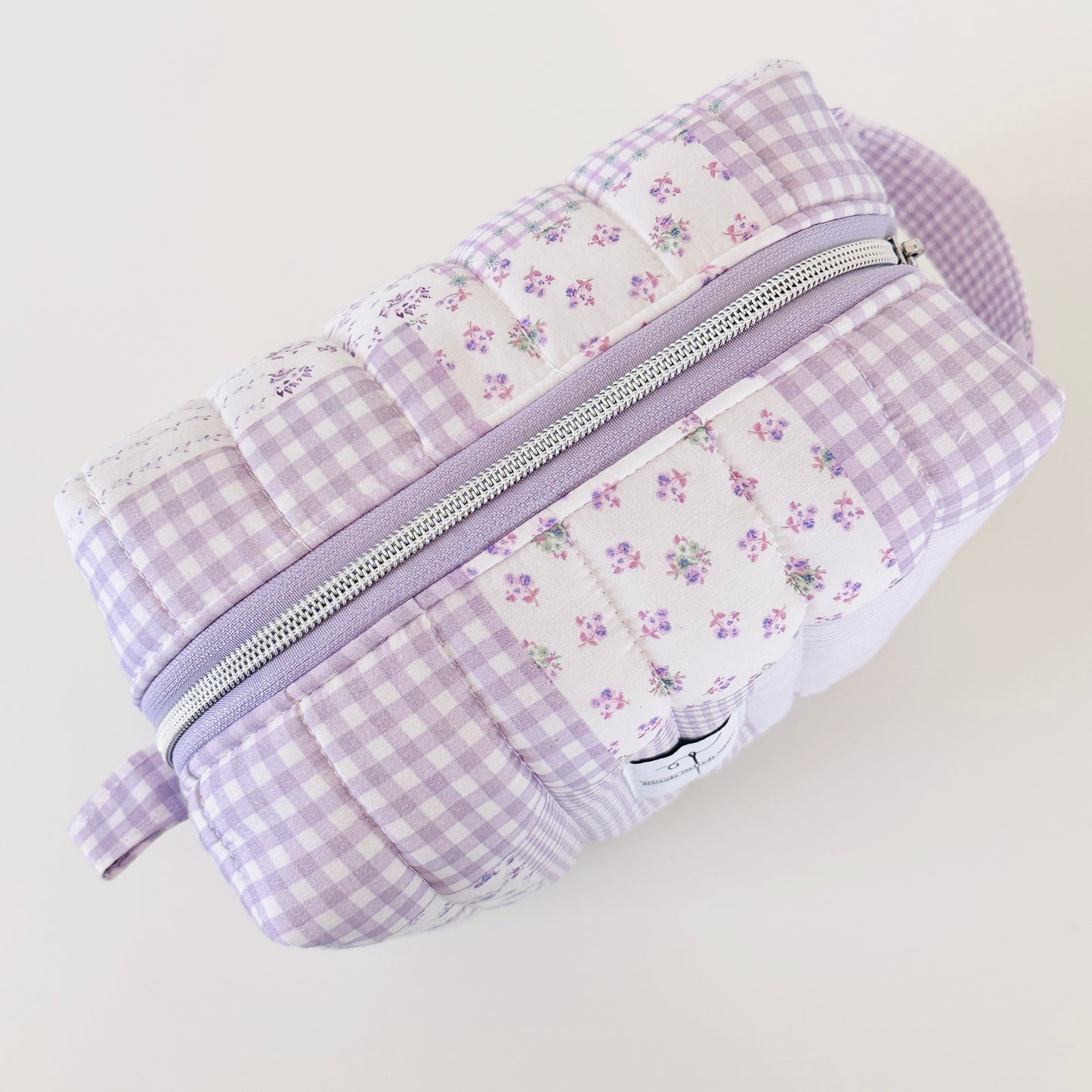 Patchwork pouch with floral and gingham patterns on a light background