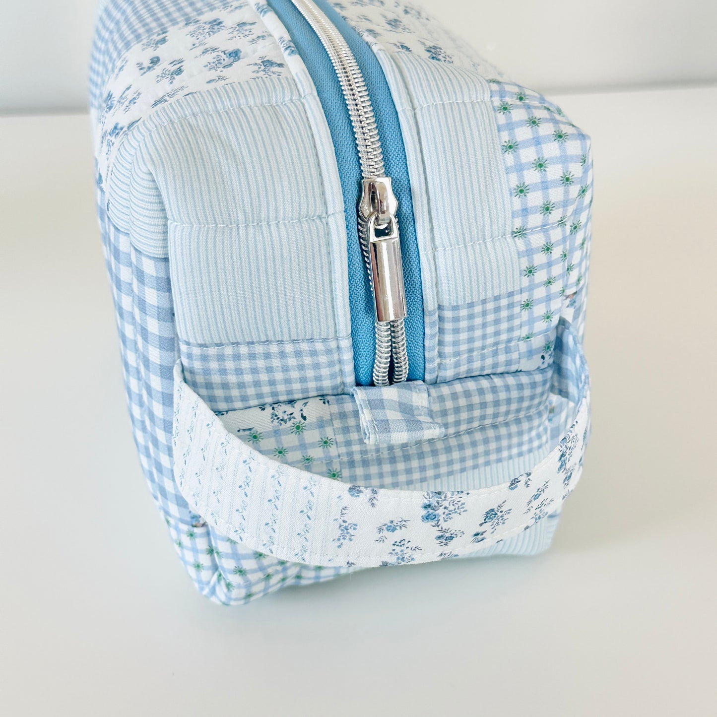 Blue and white checkered bag with floral patterns on a light gray background