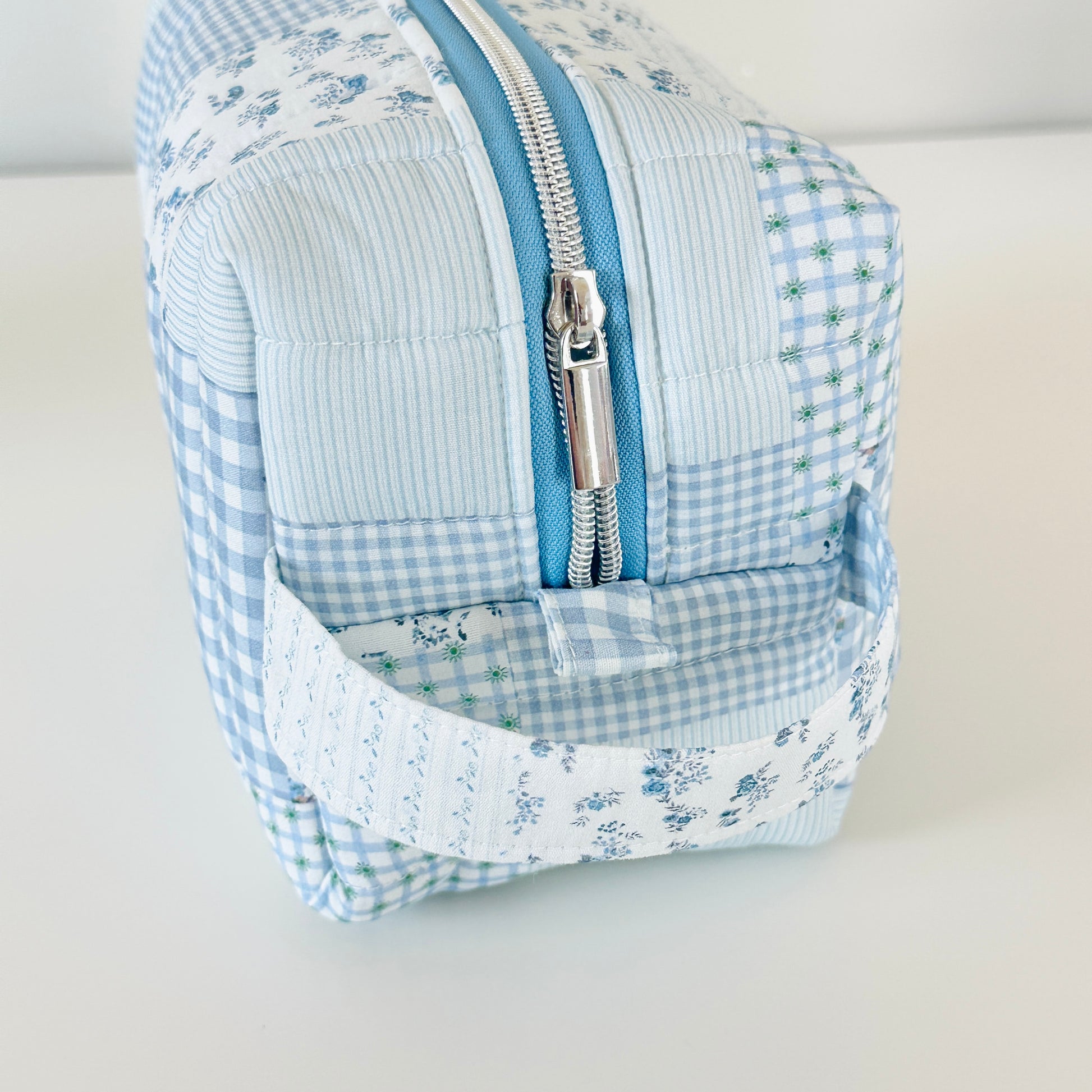 Blue and white checkered bag with floral patterns on a light gray background