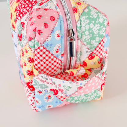 Patchwork-style fabric cosmetic bag with strawberry pattern on a light background