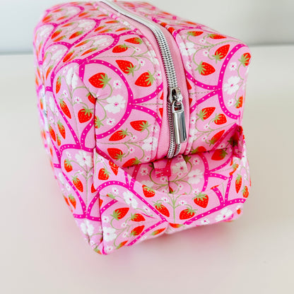 Pink cosmetic bag with strawberry pattern on a white background