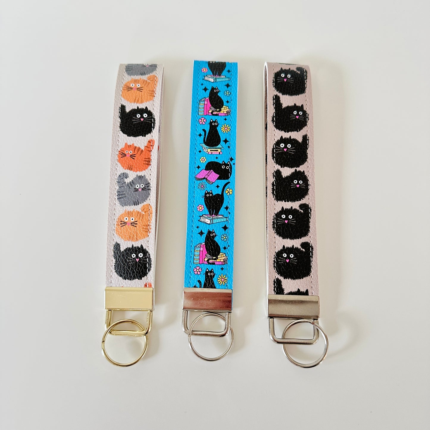 Three keychains with cat patterns on a white background