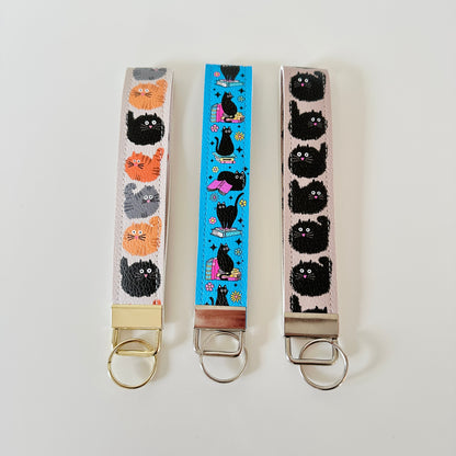 Three keychains with cat patterns on a white background